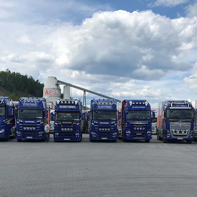 flåte av blå Volvo lastebiler parkert på rad.